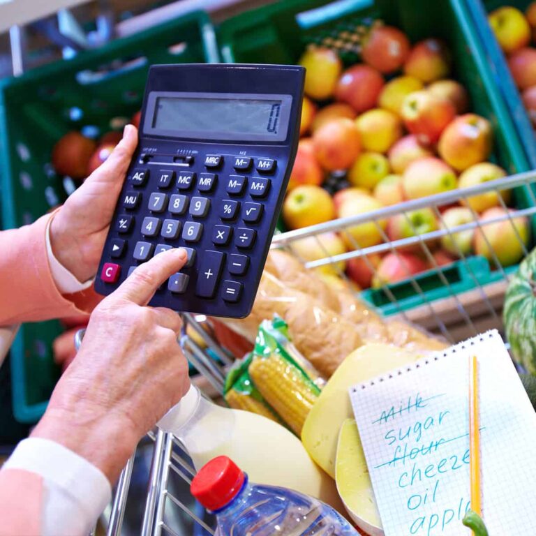 Woman using a calculator to figure grocery bill