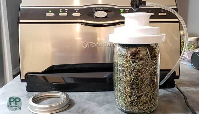 Food Saver vacuum sealer sealing a jar of dried rosemary and canning jar ring next to it