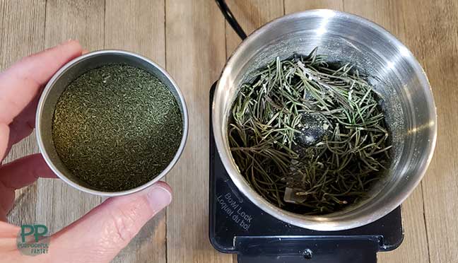 Dried rosemary in a coffee grinder next to a container full of ground rosemary.