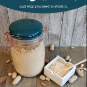 Glass jar full of peanut butter powder and dish with powder on wooden background with peanuts strewn around