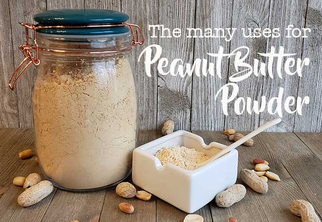 Glass jar full of peanut butter powder and dish with powder on wooden background with peanuts strewn around
