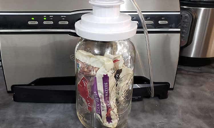 large mason jar full of packaged nuts in front of FoodSaver vacuum sealer for storing nuts