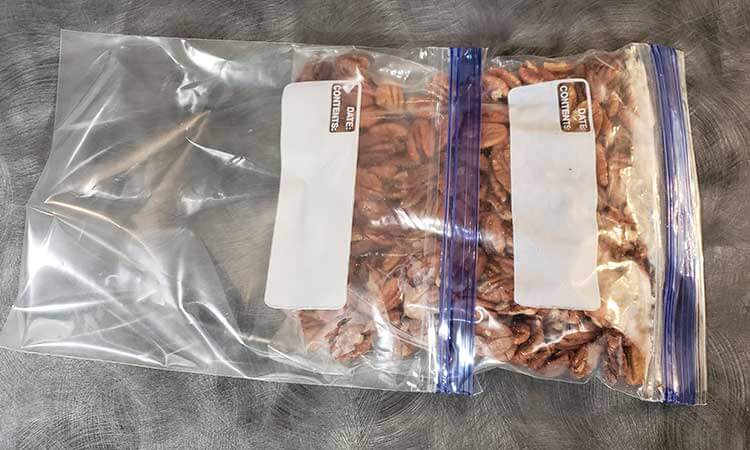 A bag of pecans being double bagged with freezer zip top plastic bags for storing nuts