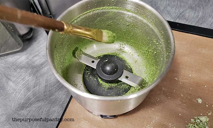 Coffee Grinder bowl full of dehydrated, powdered green scallions and an art brush to clean it with.