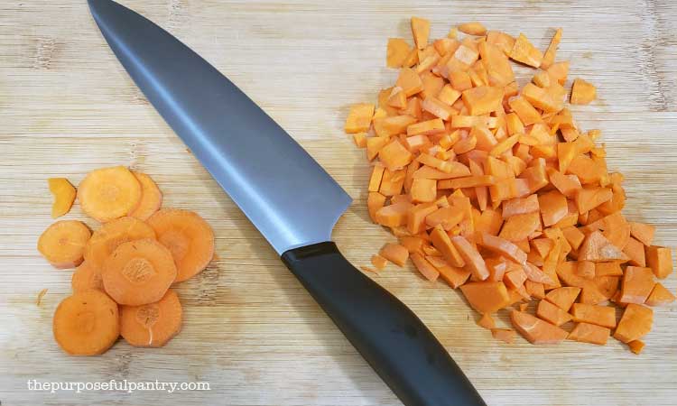 Carrot coins and chips being prepared on a cutting board to be dehydrated.