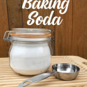 Jar of baking soda on a cutting board wit a measuring spoon with text 50 ways to use baking soda