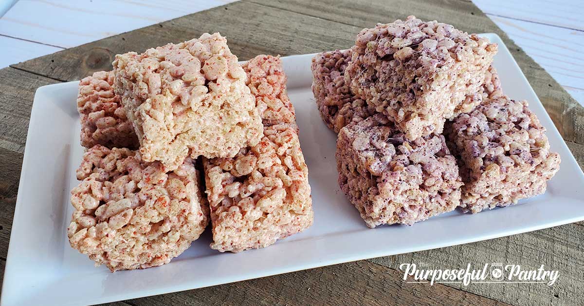 Strawberry and blueberry rice krispie treats on a white tray setting on a wooden background