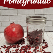 Pomegrate and jar of dehydrated pomegranate arils on white background