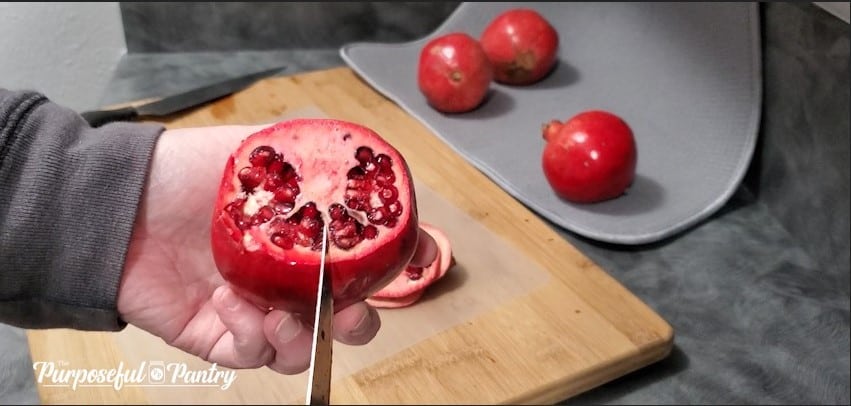 Red pomegranate over cutting board showing natural segments