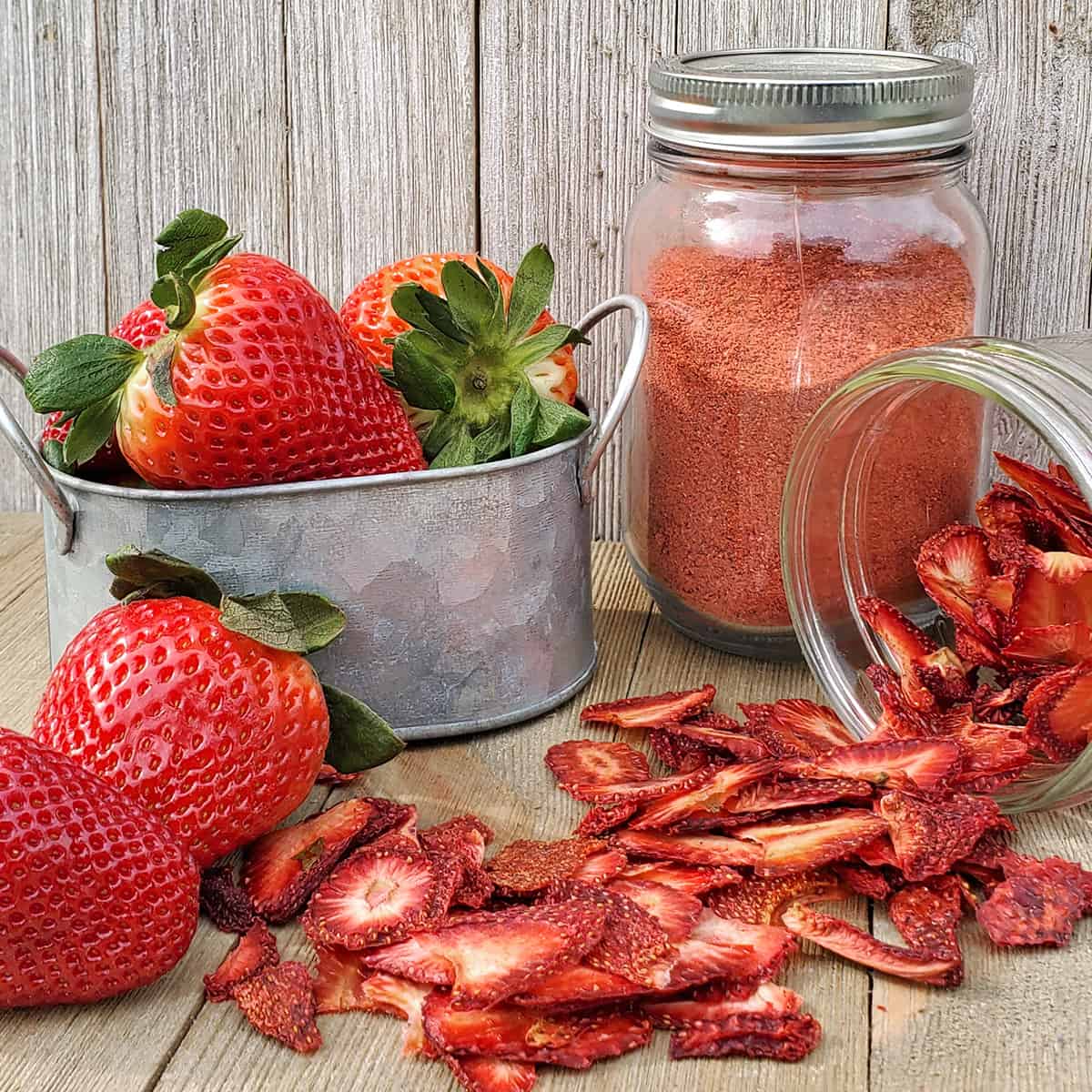 Fresh strawberries, dried strawberries and strawberry powder in containers on a wooden table