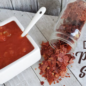 Square serving dish full of picante sauce and dehydrated picante sauce chips on wooden surface