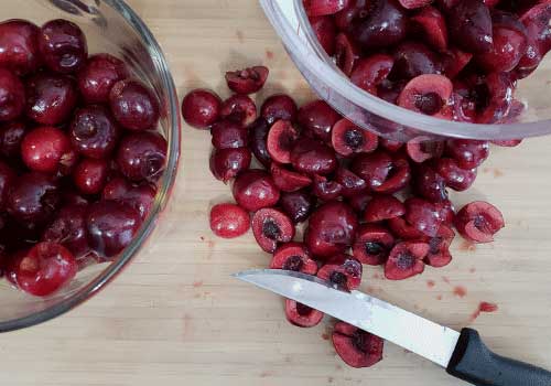 Cutting fresh cherries on a wooden cutting board