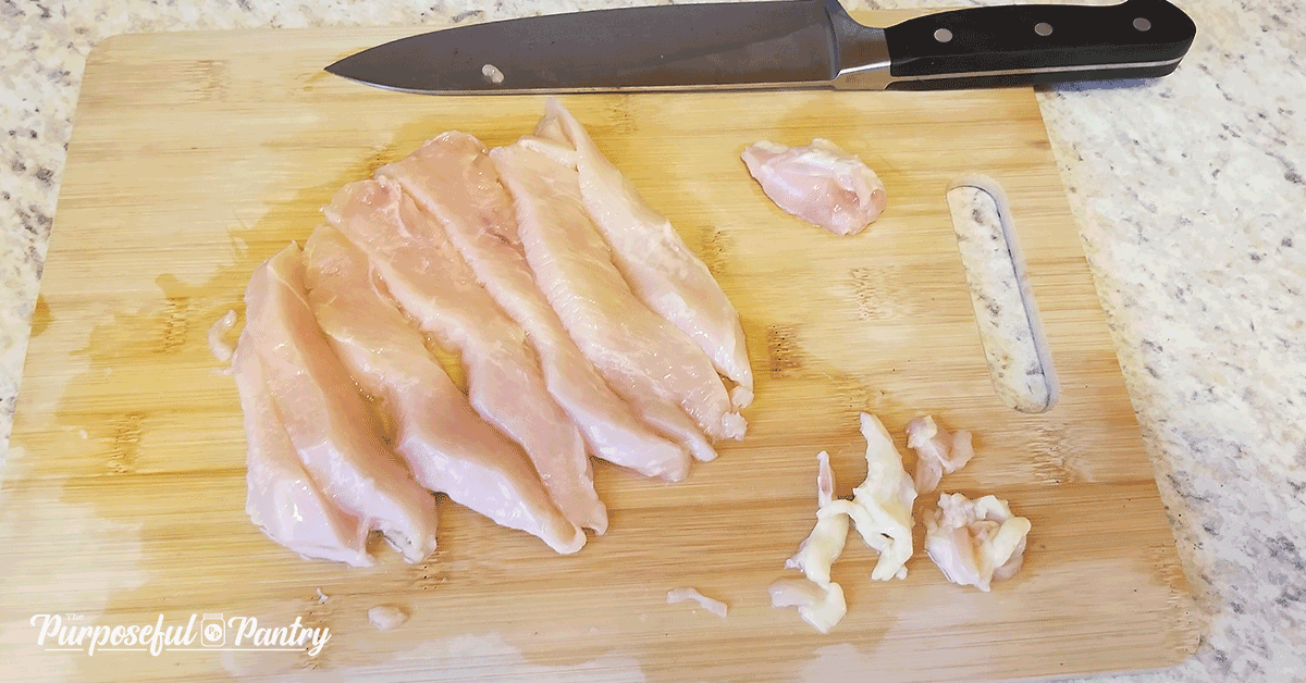 Raw chicken slices on a wooden cutting board with a knife