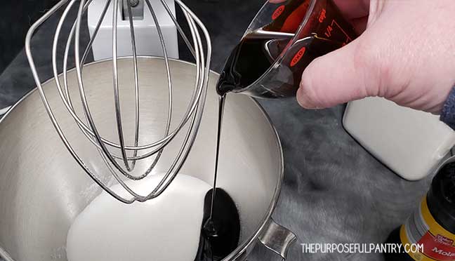 Pouring molasses into a Kitchen Aid mixer full of sugar to make homemade brown sugar