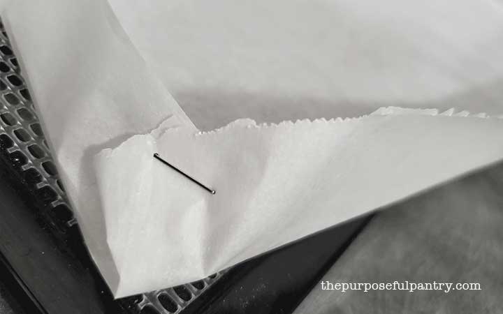 Corner of a diy homemade fruit leather tray made from parchment paper and staples