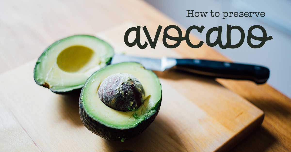 Fresh avocado that is halved with a knife on a wooden cutting surface
