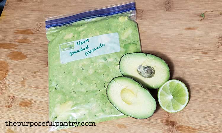 fresh avocado halved, with lime, and a bag of smashed avocado for the freezer