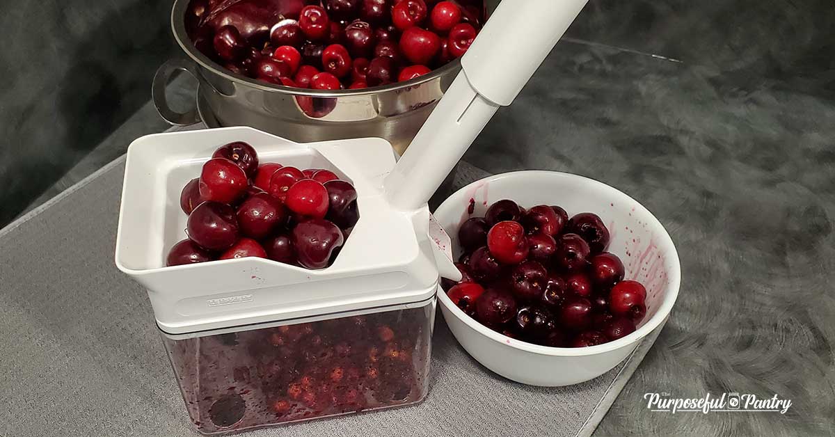 Fresh cherries in a white cherry pitter