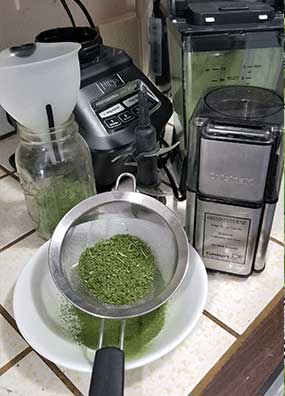 greensd in a sifter to remove stems next to a coffee grinder and blender