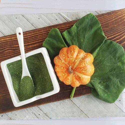 Pumpkin leaf powder on a wooden base with a decorative pumpkin and pumpkin leaf.