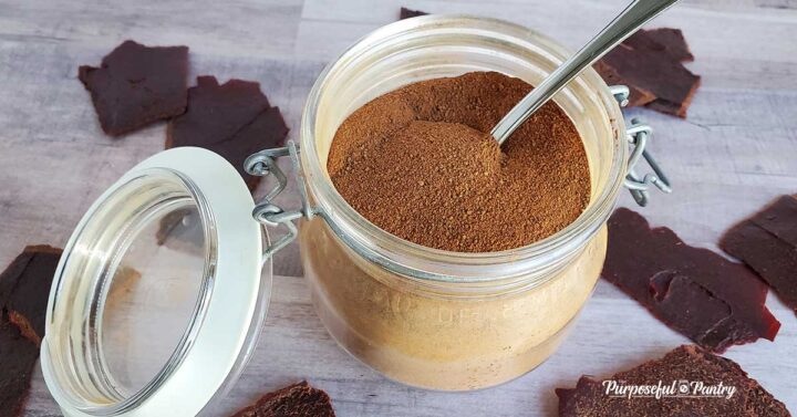 Tomato powder in a glass jar with spoon, tomato leather on wooden background