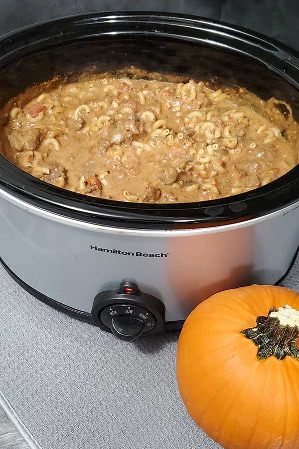 Slow cooker full of supper with a pumpkin next to it