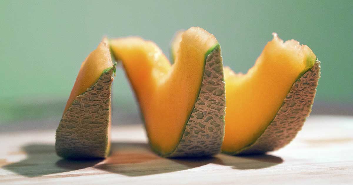 sliced muskmelon on a tabletop with blue background