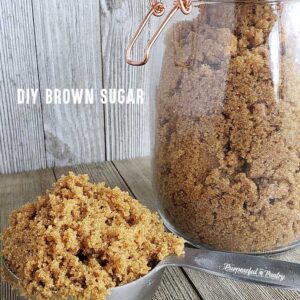 measuring spoon full of homemade brown sugar and a jarful behind it all on wooden surfaces