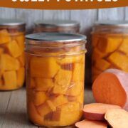 Mason jars of canned sweet potatoes on a wooden background