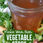 Jar of vegetable broth sitting on a bed of fresh vegetables