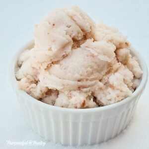 A white bowl full of strawberry snow ice cream on a bed of fresh snow