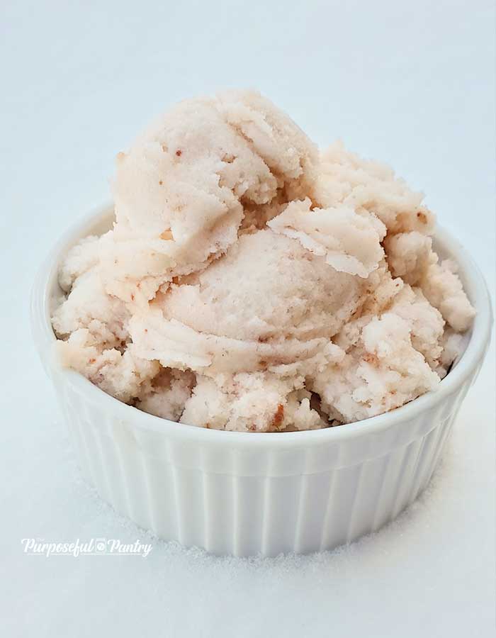 A white bowl full of strawberry snow ice cream on a bed of fresh snow