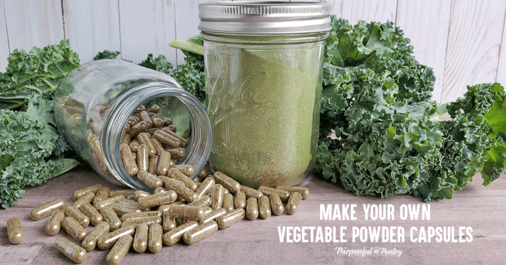 Bottle of vegetable powder capsules spilling in front of jar of dehydrated green powder in front of fresh greens.