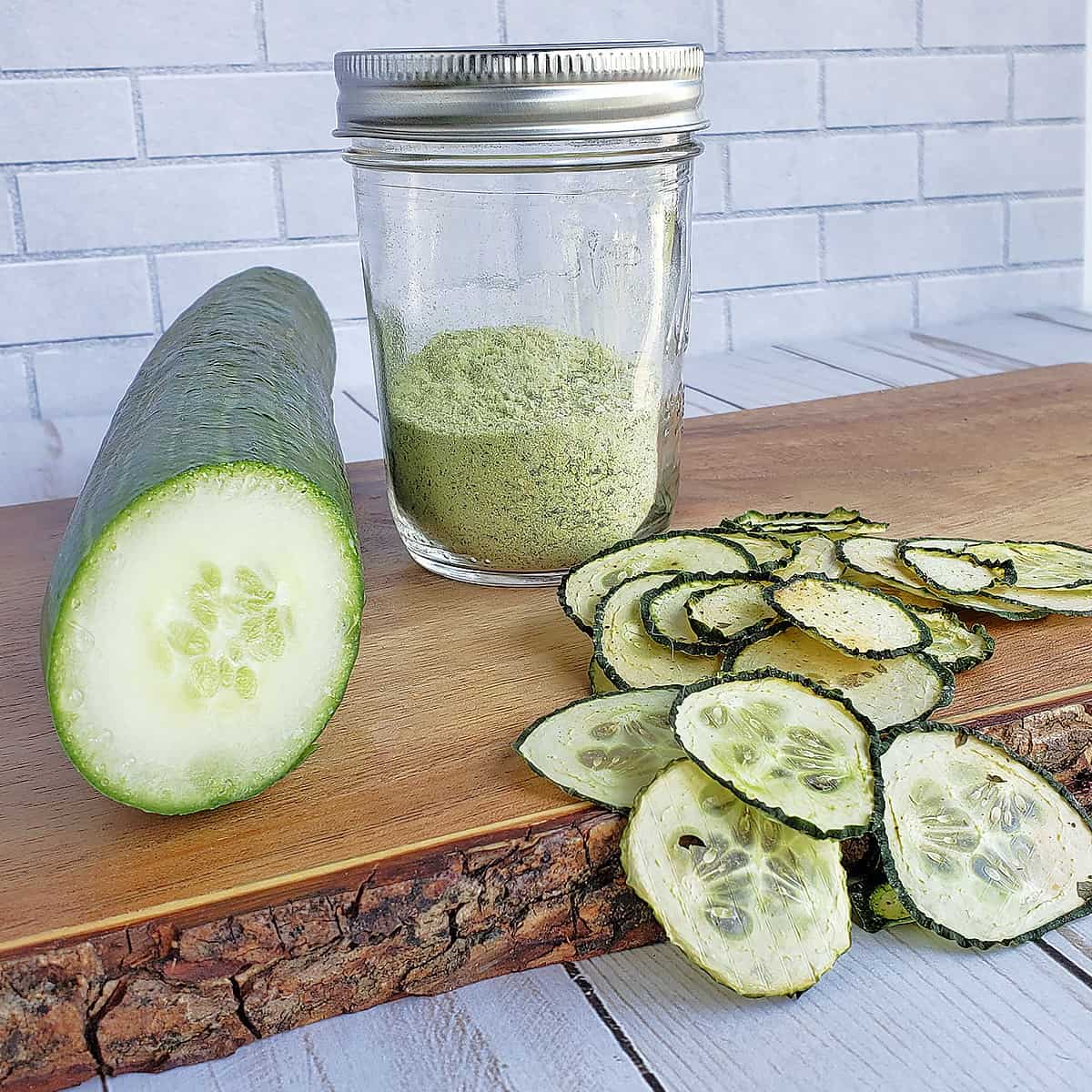English cucumber sliced, a jar of cucumber powder, and dehydrated cucumbers on a wooden serving tray