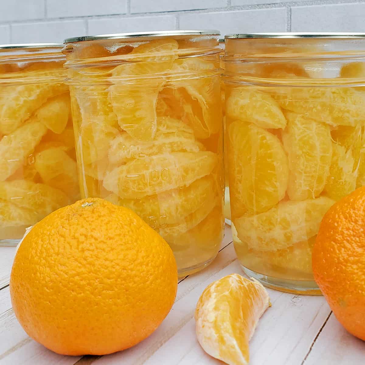 Canned jars of madarin organes and a fresh orange.