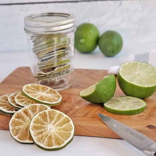 Dehydrated limes in a jar, on a cutting board with freshly cut limes
