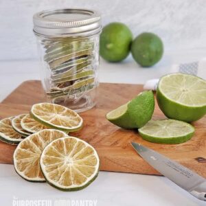 Dehydrated limes in a jar, on a cutting board with freshly cut limes