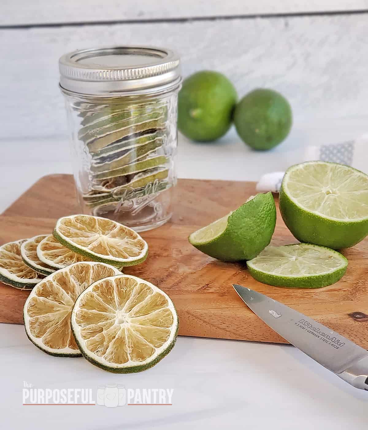 Dehydrated limes in a jar, on a cutting board with freshly cut limes