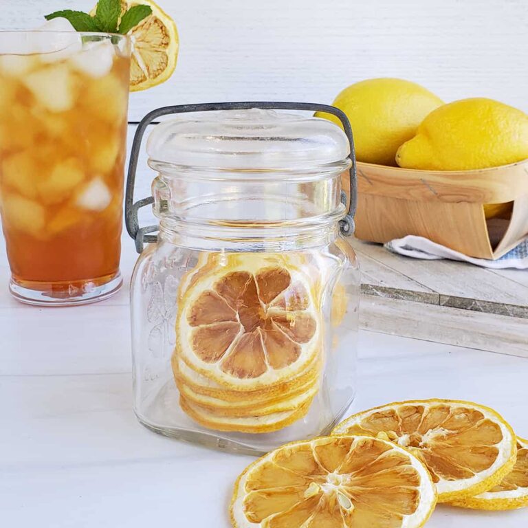 Dried lemon slices in a jar, on the table, and one in a glass of iced tea.