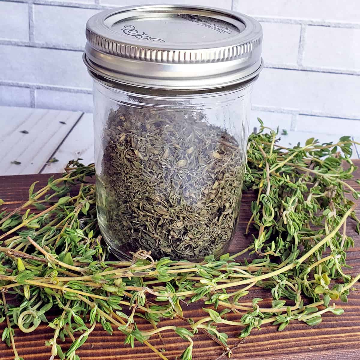 Dried time in a storage jar on a bed of fresh thyme on a wooden surface
