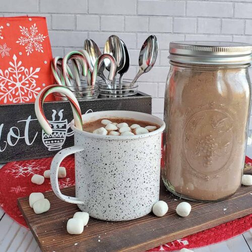 Hot cocoa in a cup with a bulk hot cocoa mix in a mason jar