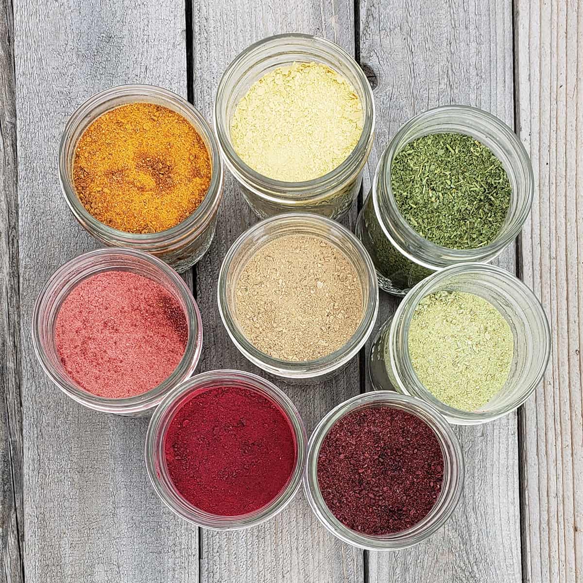 Various vegetable and fruit powders in the colors of the rainbow in circle on a wooden surface