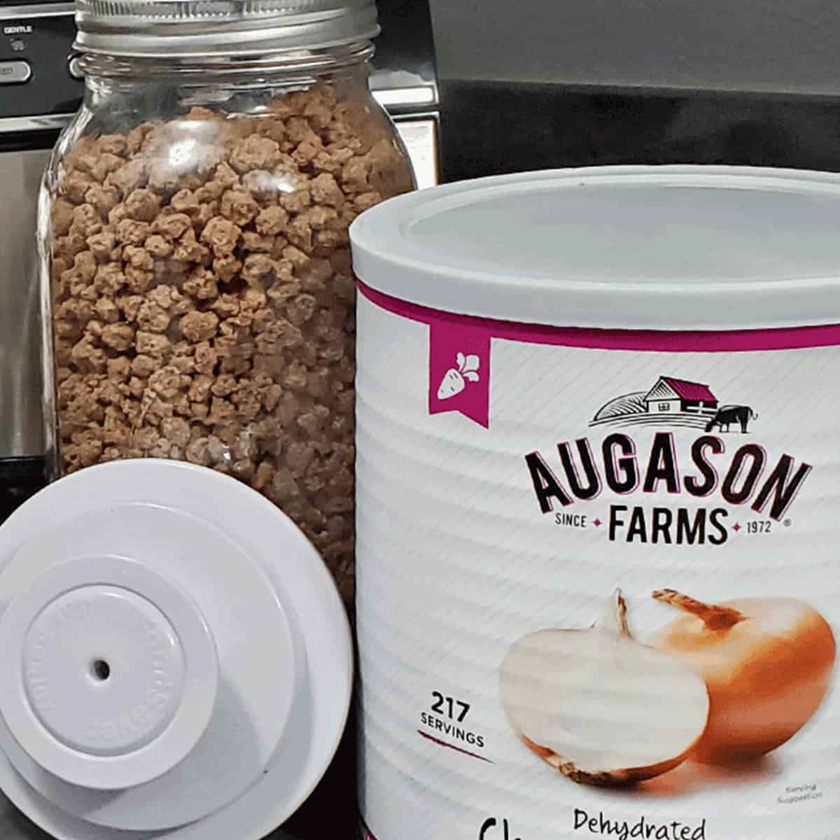 Jar of freeze dried ground beef, a foodsaver vacuum lid and #10 can of Augason Farms dehdyrated onion