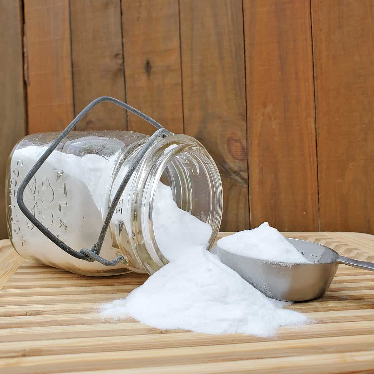 Baking powder in a small antique canning jar spilling onto a wooden surface