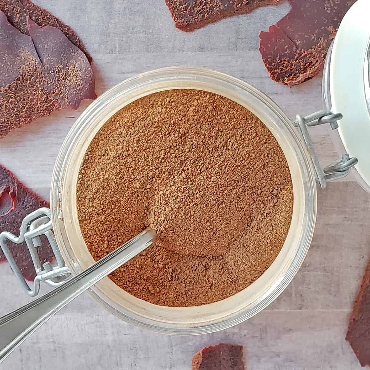 A jar of tomato powder made from tomato paste on a wooden background