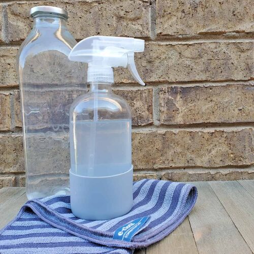 Bottle of vinegar, spray bottle of vinegar cleaner and blue washcloth