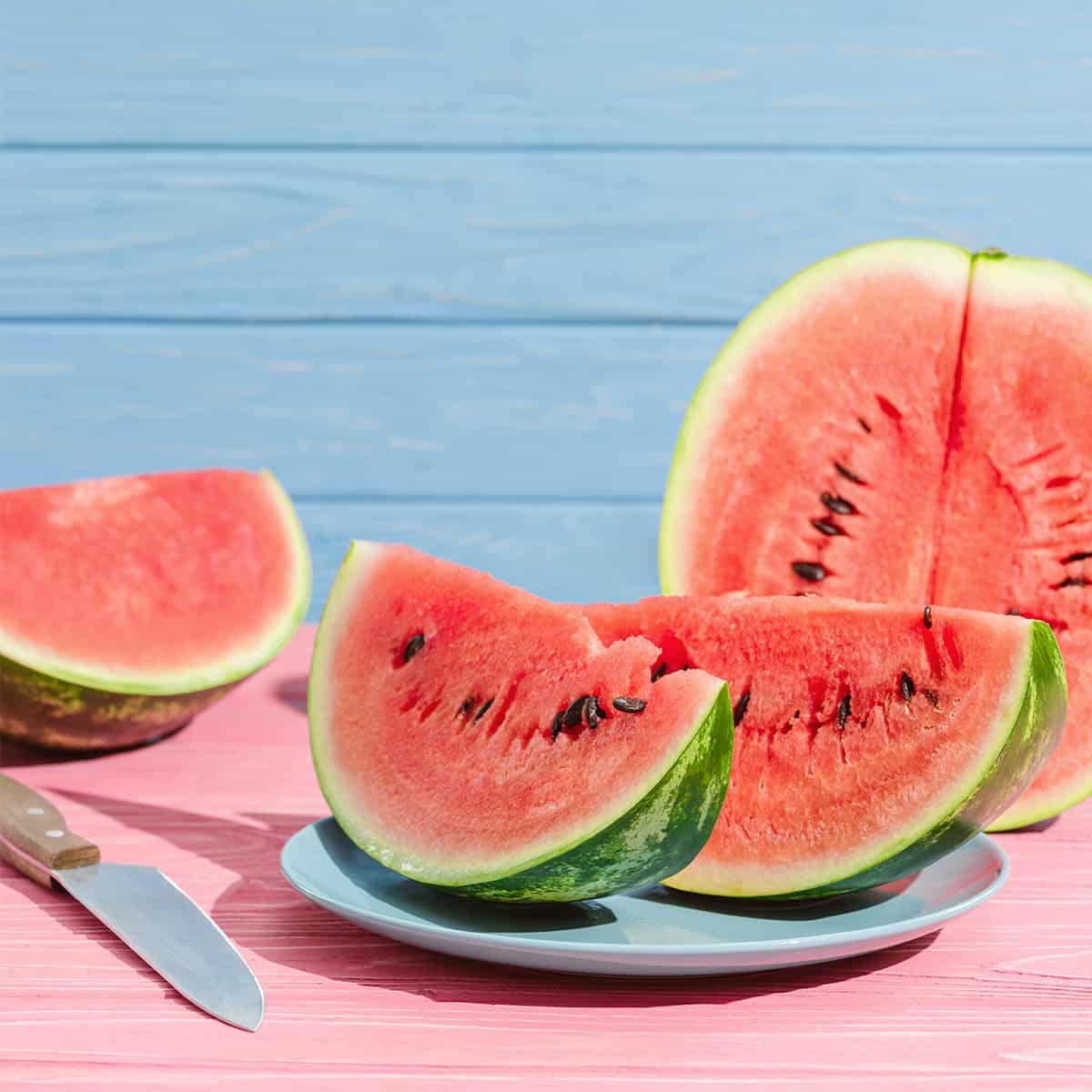 Watermelon sliced, halfed, and served on blue dinnerware