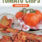 Dehydrated tomato chips on a wooden table with fresh tomatoes in the background