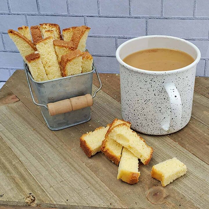 pound cake biscotti on a wooden surface with a cup of coffee in white speckled mug