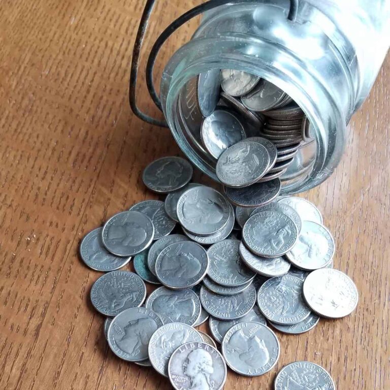 Jar of quarters spilled out onto a table signifying an emergency fund